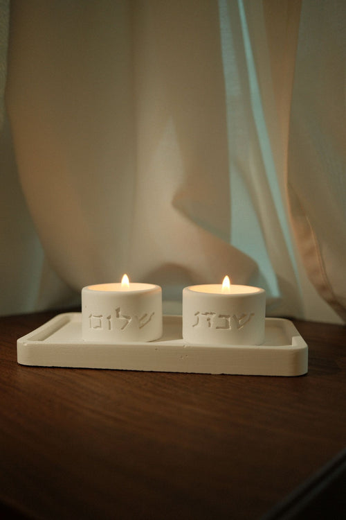House of Judaica white Shabbat candle tray with Hebrew lettering and lit candles
